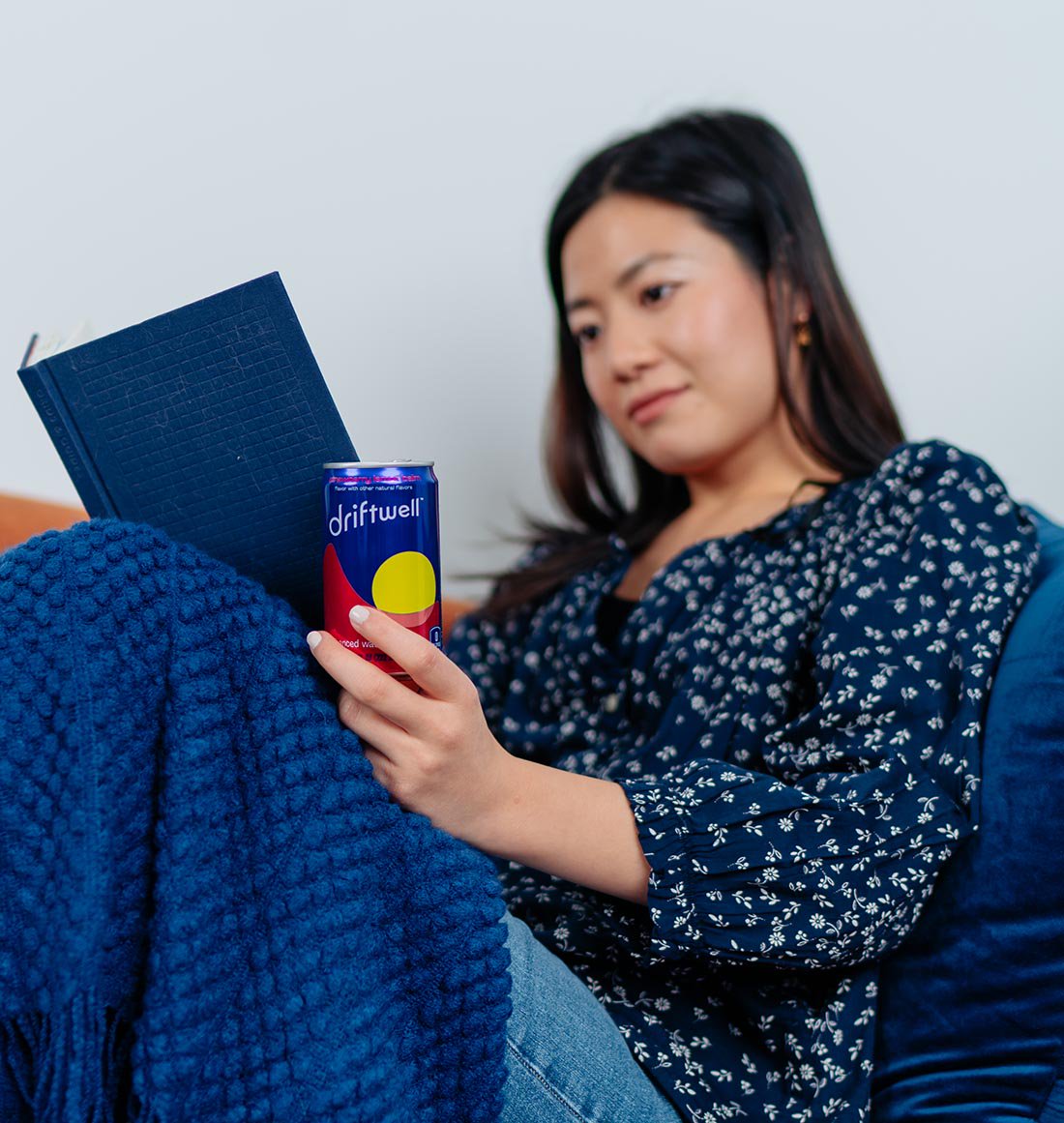 Woman reading a book with a can of Driftwell