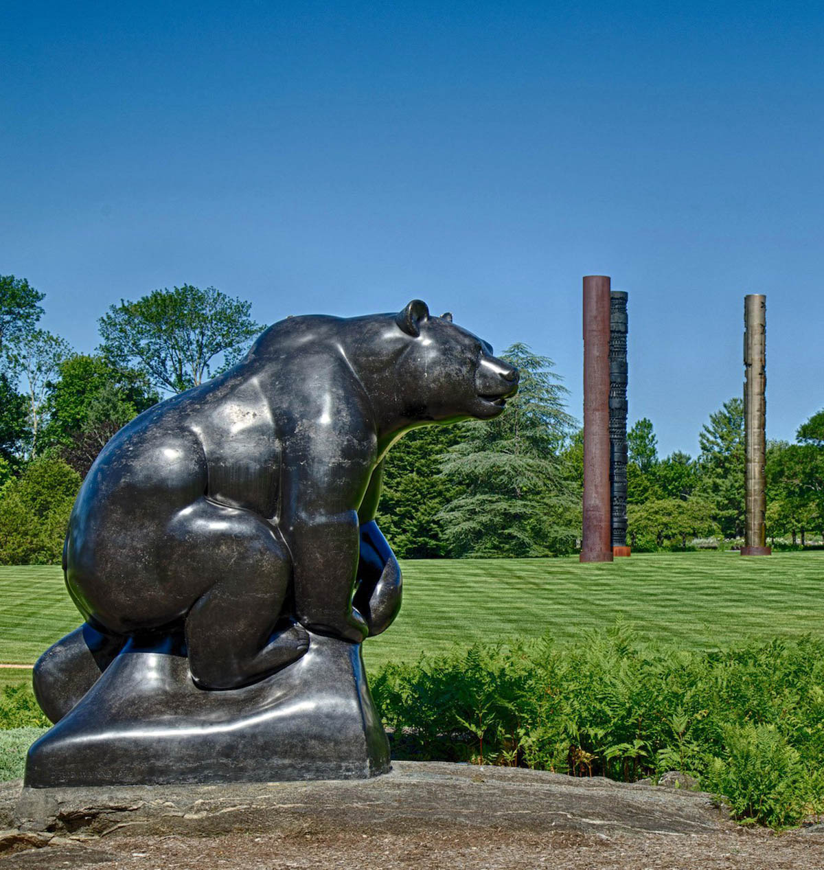 David Wynne's "Grizzly Bear" stands on the shore of the lake with Arnaldo Pomodoro's "Triad" in the distance