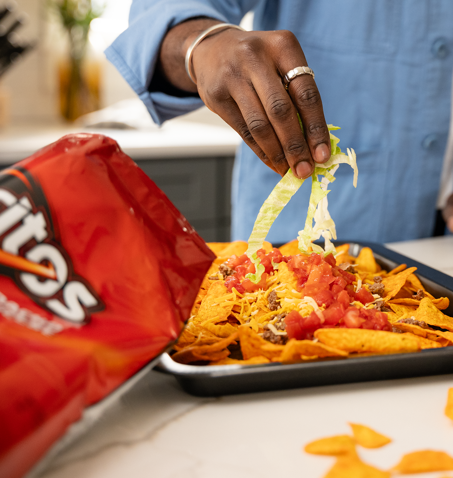 Man adding toppings to Doritos nachos