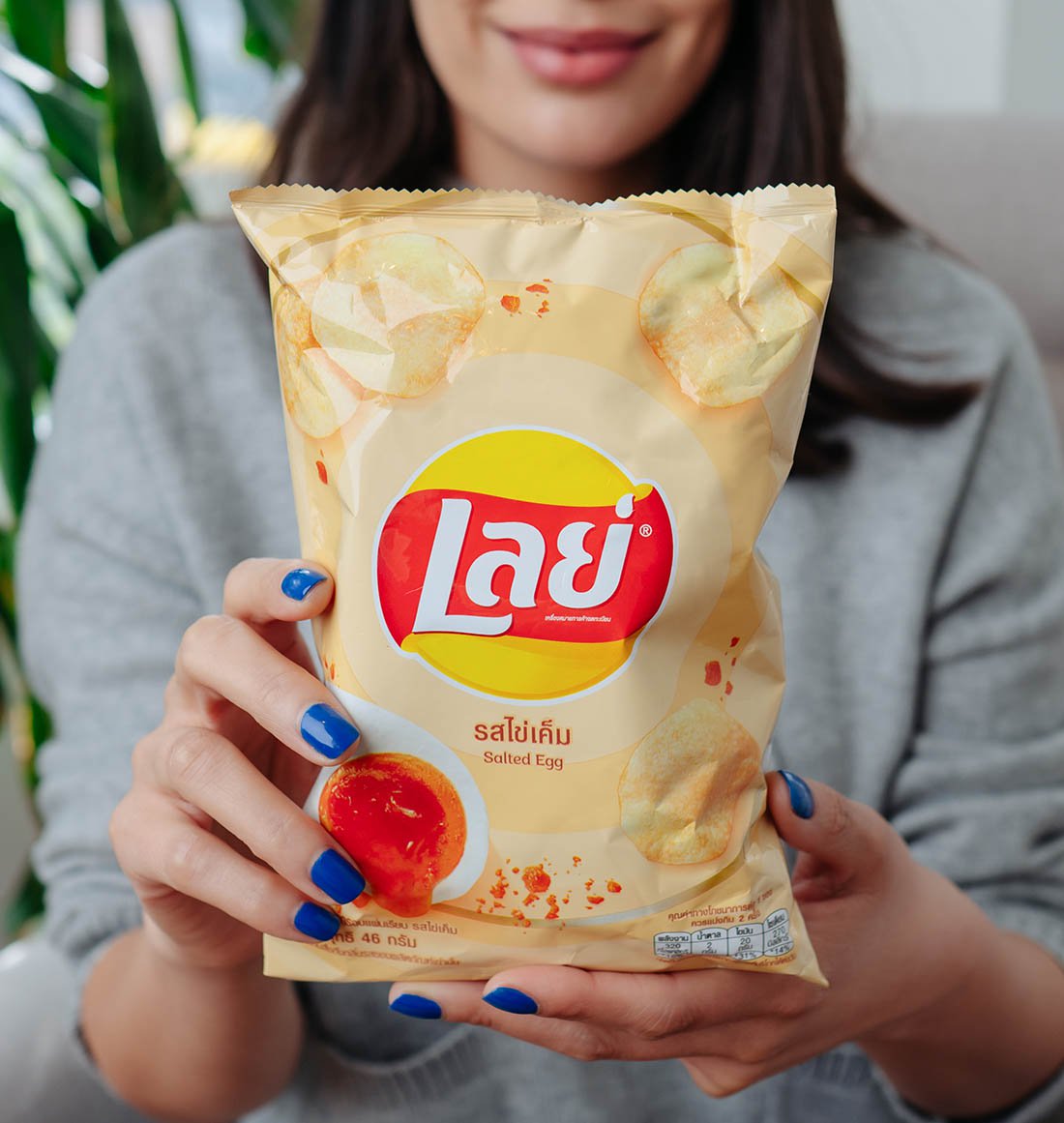 Woman holding up a bag of Lay's Salted Egg chips from Thailand