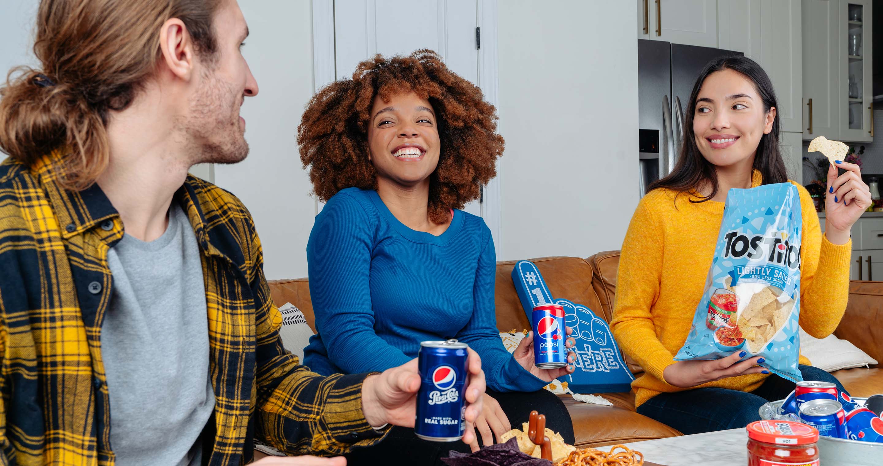 Friends celebrating a win for the home team with Tostitos and Pepsi