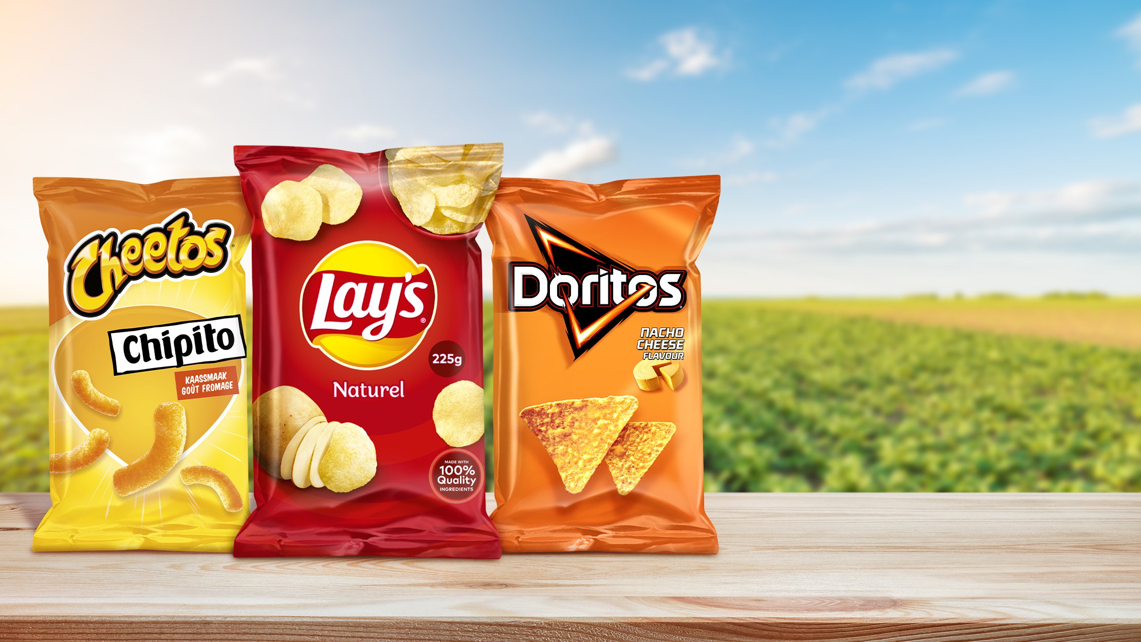 Cheetos, Lay's, and Doritos bags sitting in front of a farming field