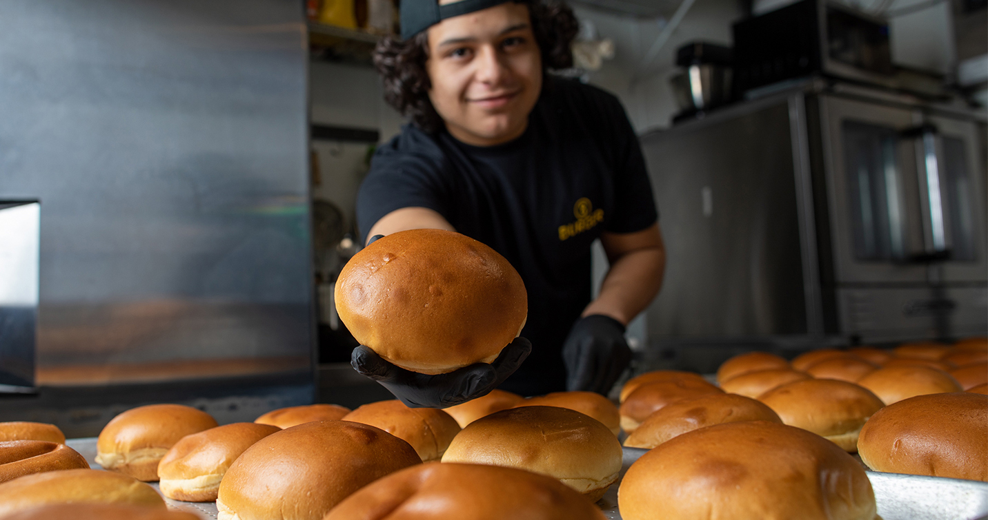 Miguel Daza holds out a homemade 8 Burger bun