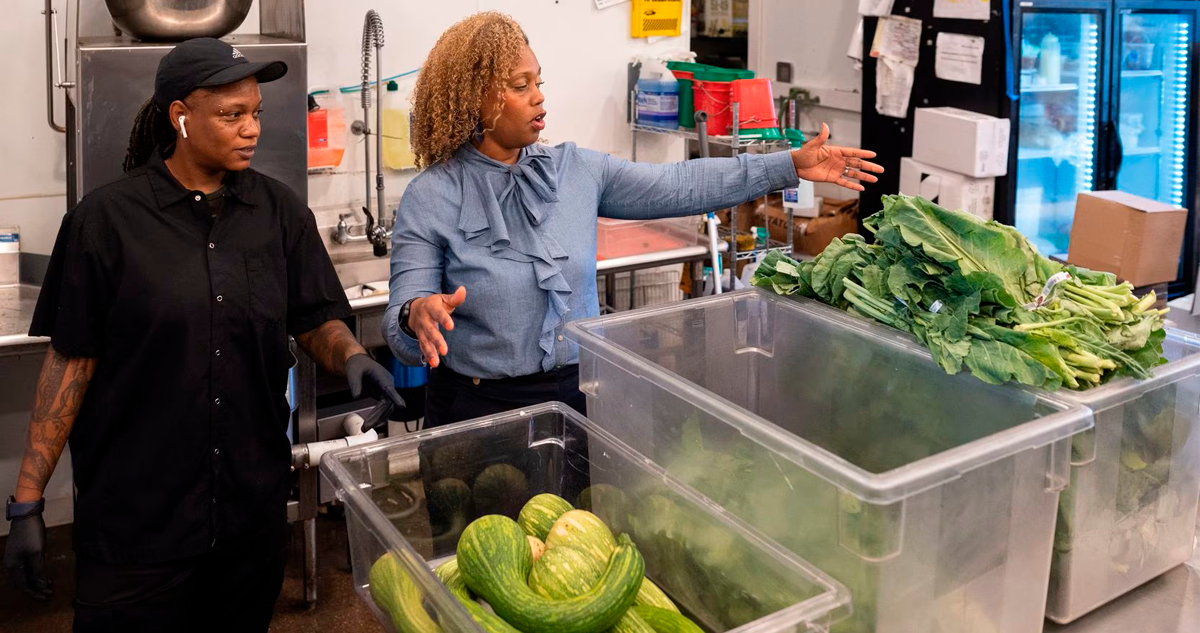 Gabe standing next to a table of Bonton Farms vegetables.