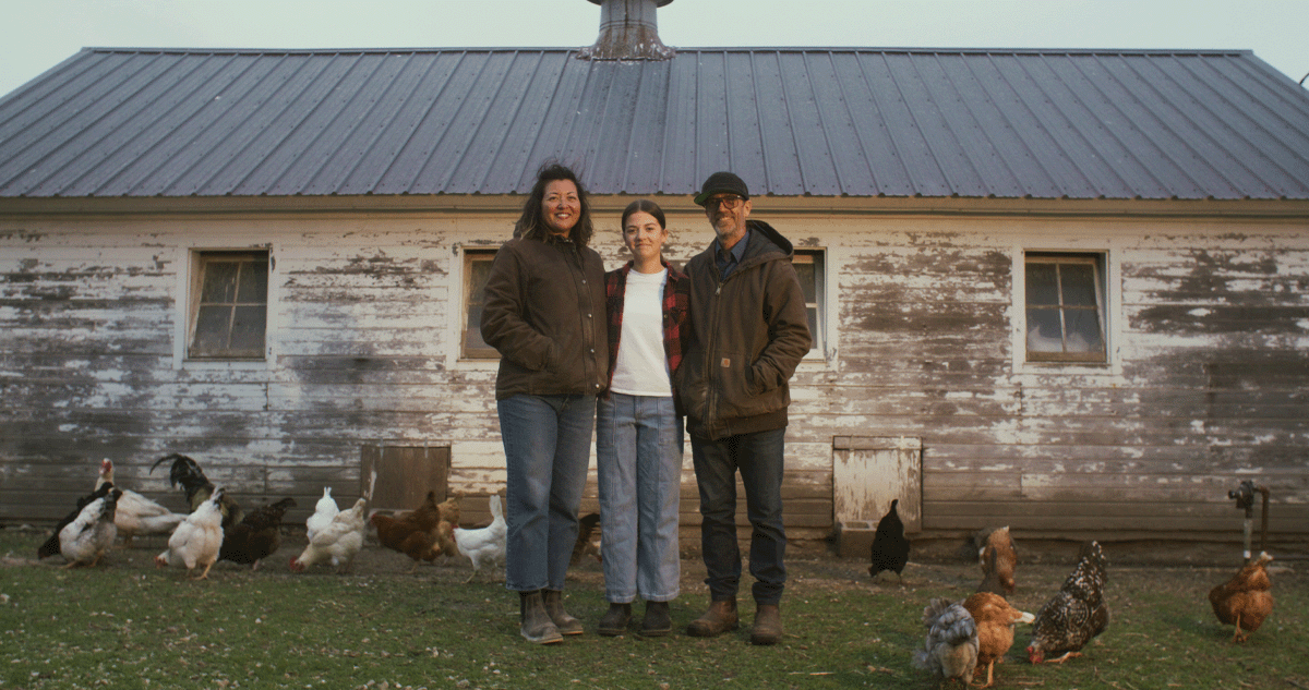 Wendy Johnson standing with her daughter and husband surrounded by chickens