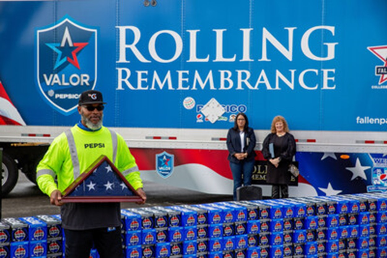 PepsiCo associate holding American flag in front of PepsiCo Valor Rolling Remembrance truck