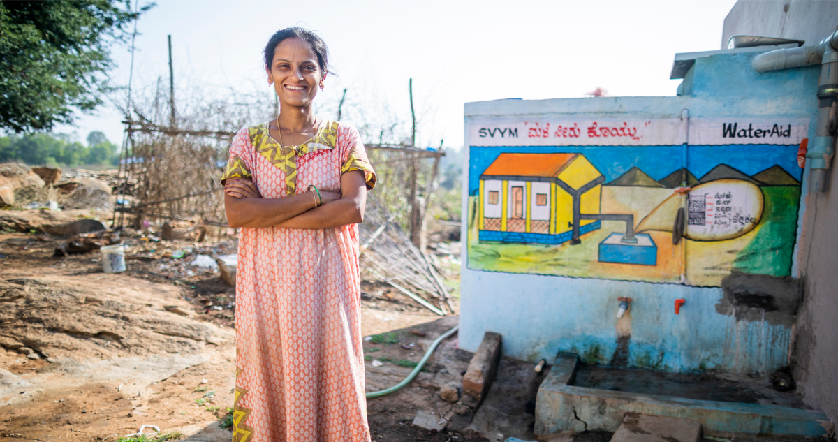 Prema Devaraju standing next to a water storage tank.