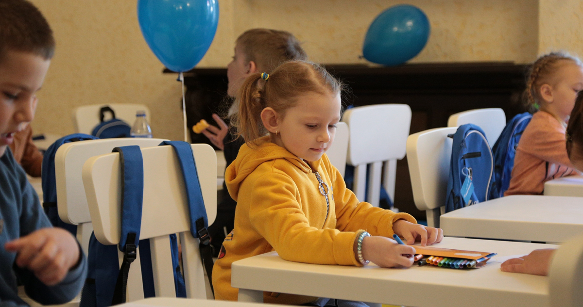 A young girl coloring on a table with other kids